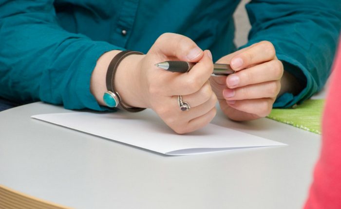 a person sitting at a table writing on a piece of paper